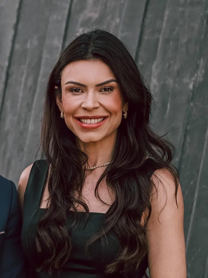 Dra. Emanuelle Jamille, sorrindo, de vestido escuro